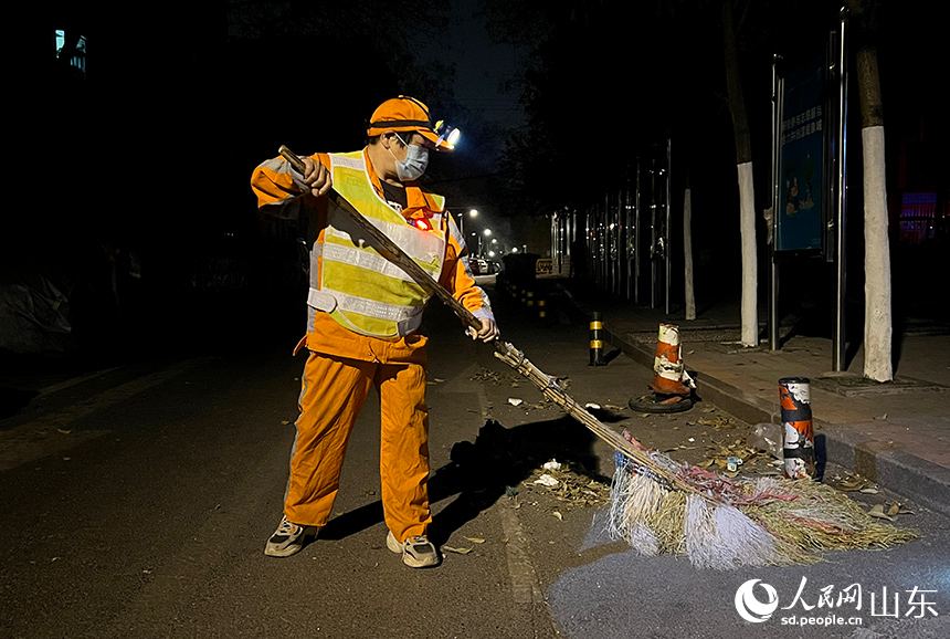 王海菊借著路燈光開始清掃道路。人民網(wǎng) 劉祺攝