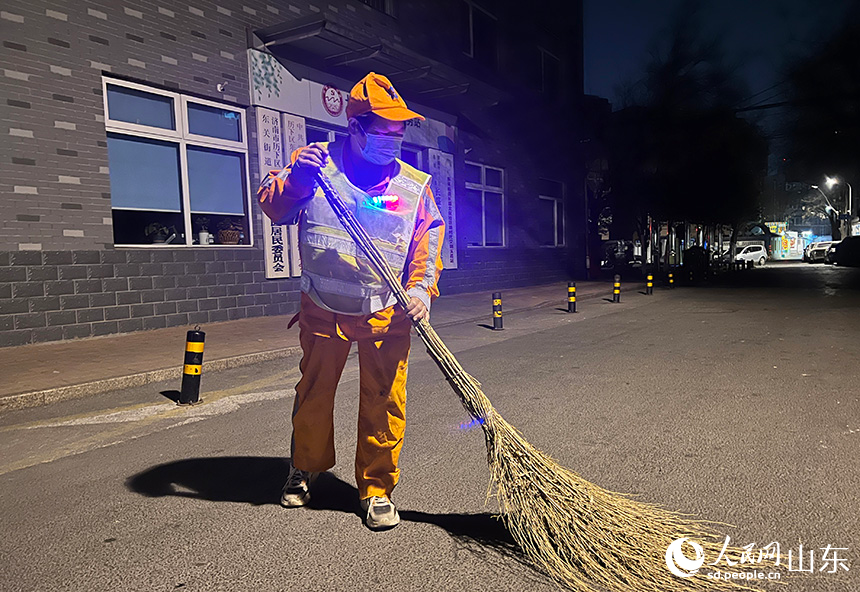 王海菊借著路燈光開始清掃道路。人民網(wǎng) 劉祺攝