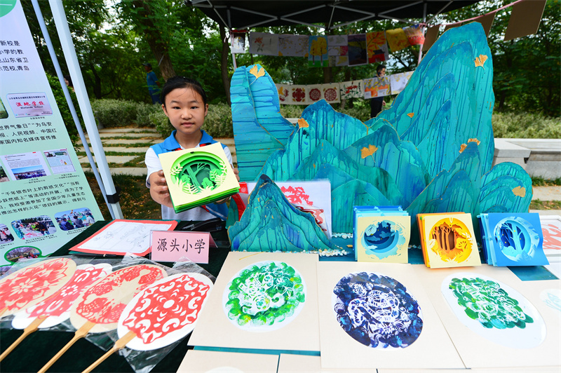 一名源頭小學(xué)的學(xué)生在展示生態(tài)剪紙作品。王海濱攝